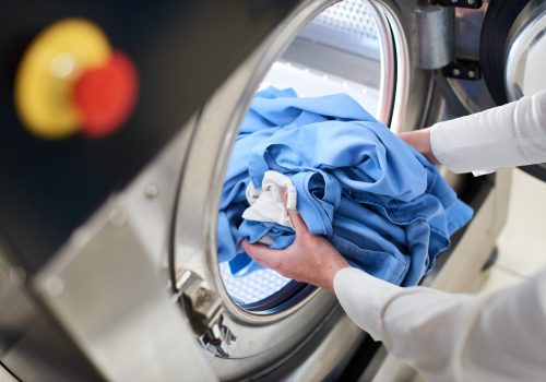 Hands loading laundry into washing machine in dry cleaning